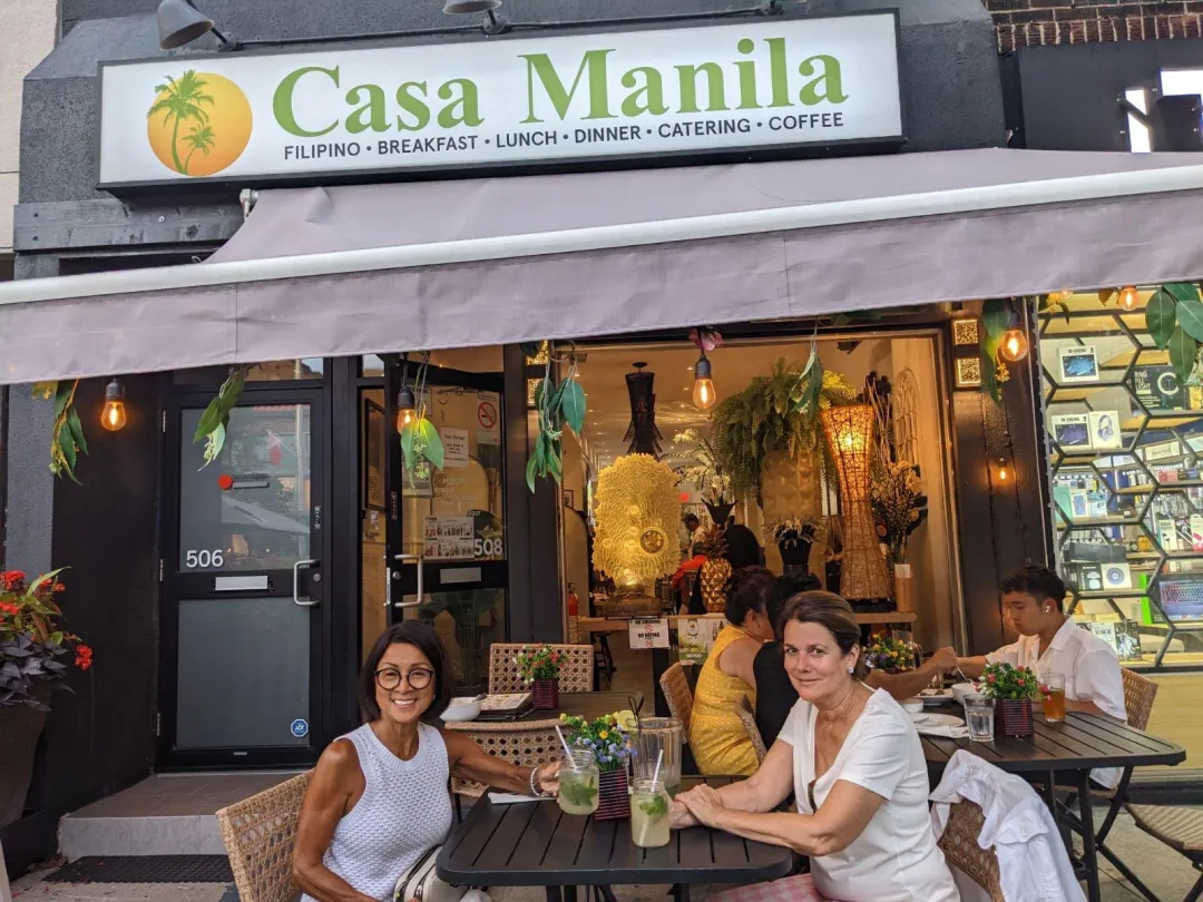 Casa Manila storefront on The Danforth at dusk — patio diners in front of the lit dining room and signage